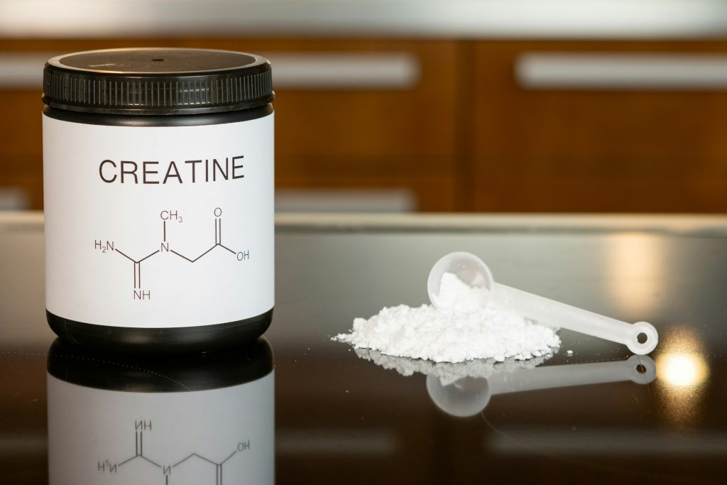 Creatine supplement powder with scoop on table for strength, brain health and performance.